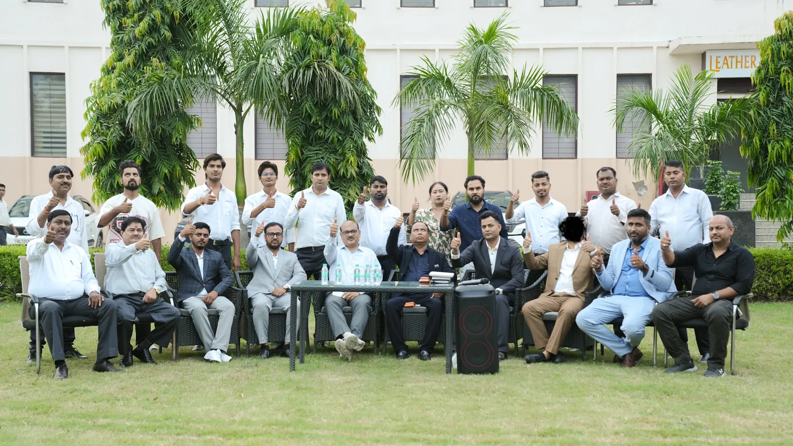LEATHER LUXURY management team seated on the factory lawn giving a thumbs up